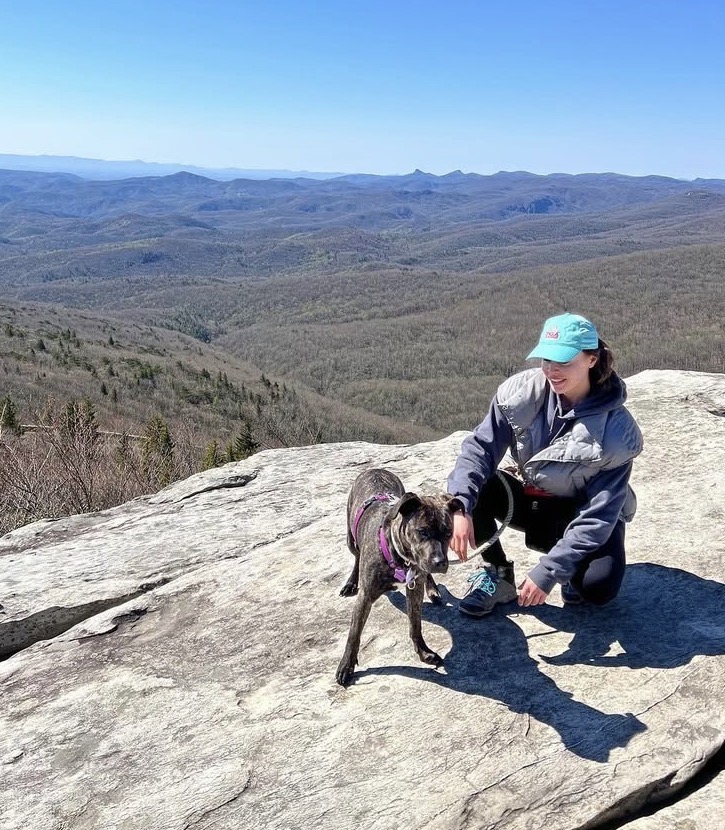 A woman with a pit bull dog on a mountain ledge