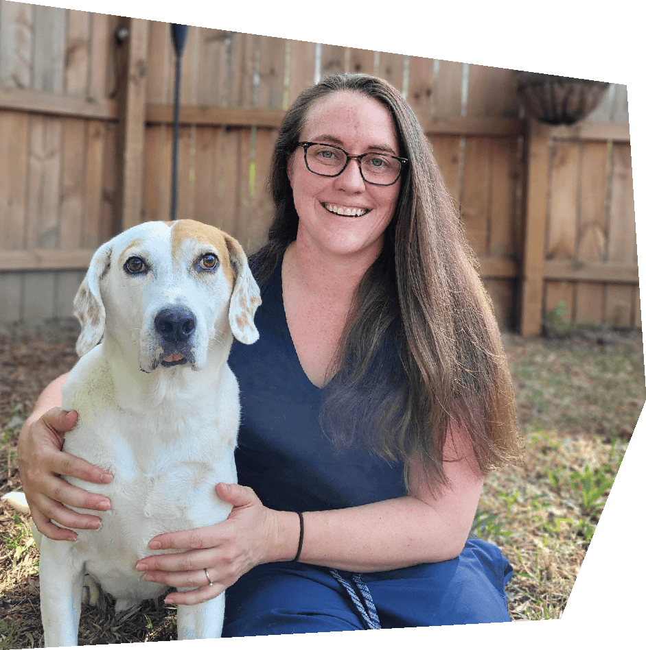 Woman sittting with a hound, smiling. 